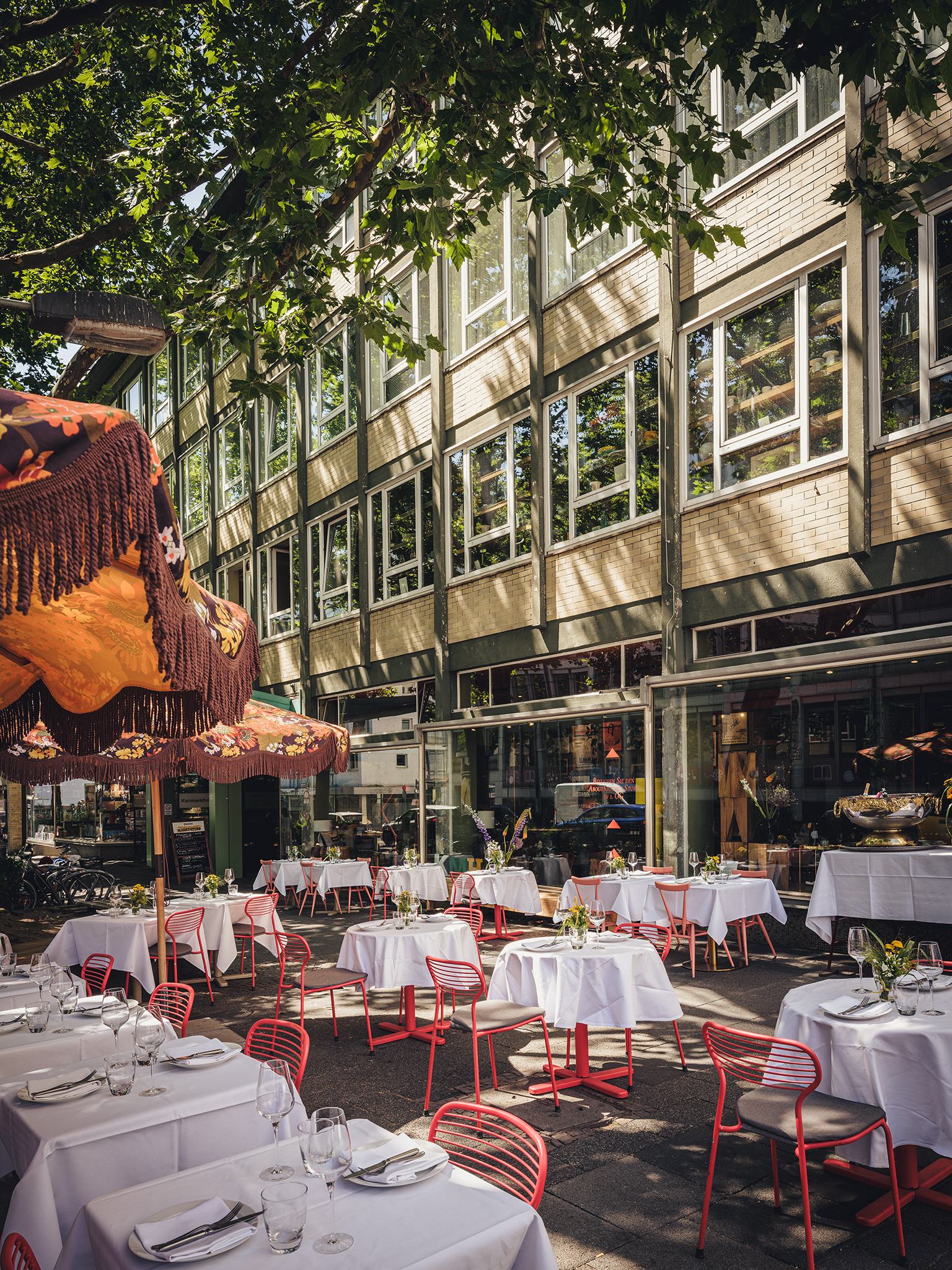 Terrasse an der Hasengasse mit roten Stühlen unter Platanen
